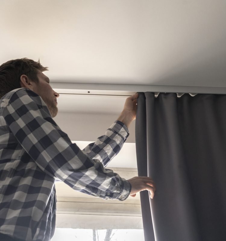 man doing house works, attach the railing and hang curtains at home