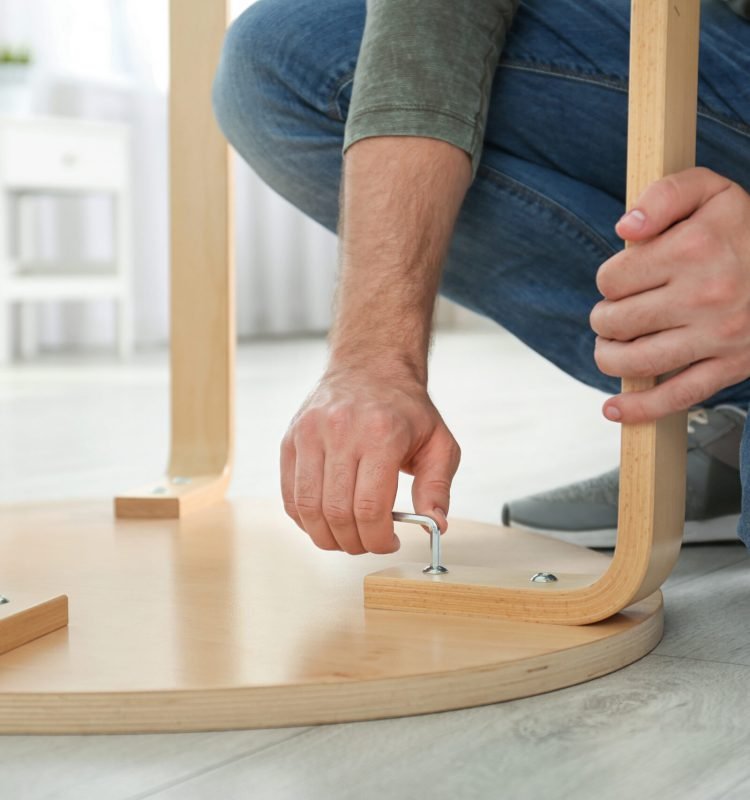 Young working man repairing table at home, closeup