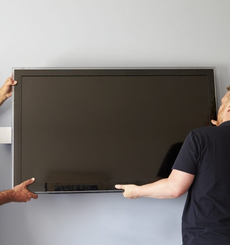 Two Men Fitting Flat Screen Television To Wall