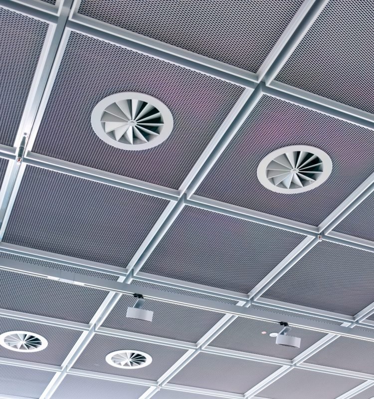 Modern ceiling pattern of white tiles and ventilation pipes, lights, smoke detectors