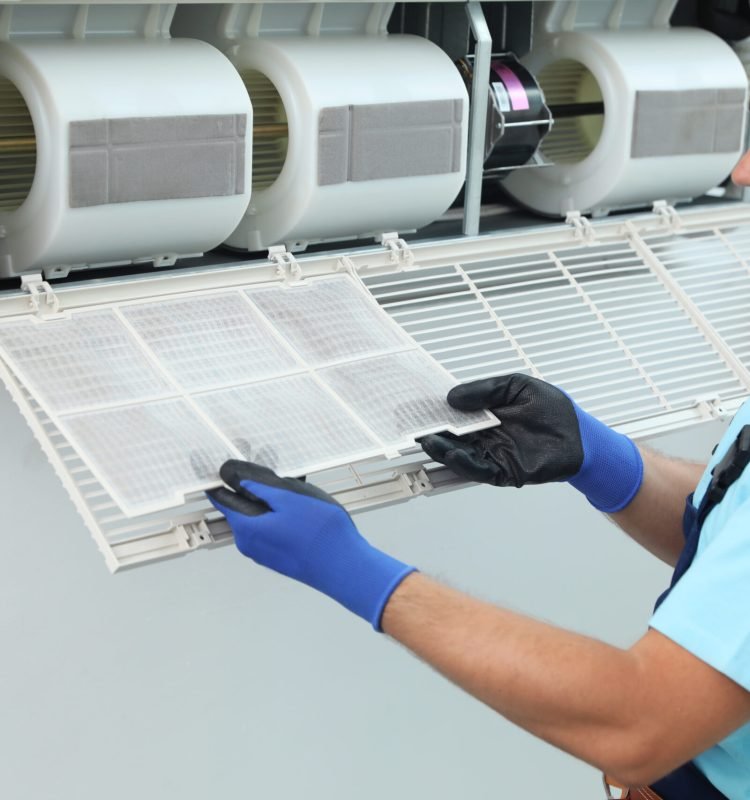 Male technician cleaning air conditioner indoors